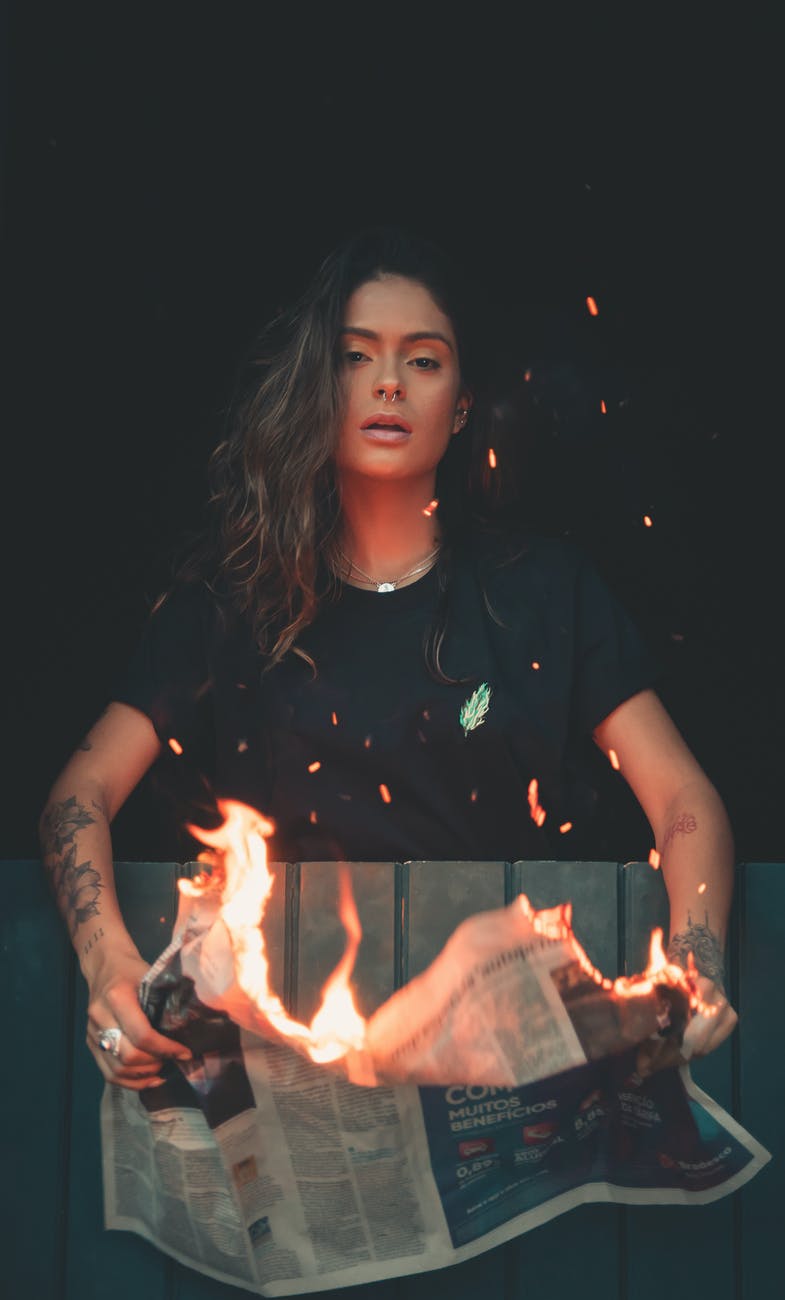 woman holding burning newspaper